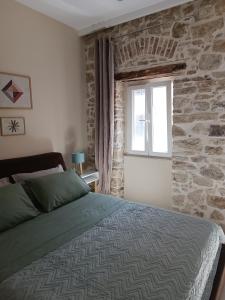 una camera con letto e parete in pietra di Beau Maison a Città di Corfù