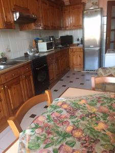 uma cozinha com armários de madeira, uma mesa e um frigorífico em Casa vacanze Gilli em Cagliari