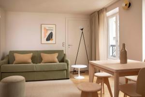 ein Wohnzimmer mit einem grünen Sofa und einem Tisch in der Unterkunft Résidence Nell Paris in Paris
