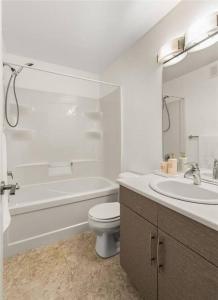 Baño blanco con aseo y lavamanos en Quiet, modern, stylish, one King & two Queen size beds, central location, parking, en Winnipeg