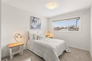 a white bedroom with a bed and a window at Quiet, modern, stylish, one King & two Queen size beds, central location, parking in Winnipeg