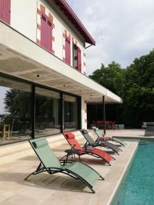 a row of chairs sitting next to a swimming pool at Les Palissières in Mortagne-sur-Gironde