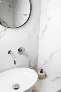 een witte badkamer met een wastafel en een spiegel bij Olivia Apartments in Pefkochori