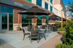 un patio al aire libre con mesas, sillas y sombrillas en The Westin Wilmington en Wilmington