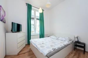 a white bedroom with a bed and a tv at Luxury Location-Bright&Parking in Łódź