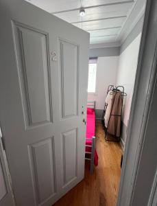 Habitación con puerta blanca y maleta rosa en Casa Flamingo, en Figueira da Foz