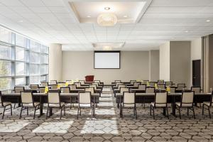 una sala de conferencias con mesas, sillas y una pantalla en Magnolia Hotel St. Louis, a Tribute Portfolio Hotel, en Saint Louis