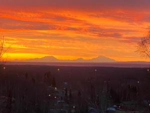 Eagle RiverにあるAlaskan Adventure Awaits!の山を背景に夕日と市街