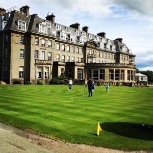 a group of people playing golf in front of a large building at Silver Birch Lodge in Auchterarder