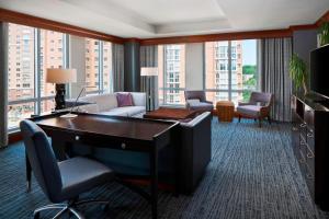 a living room with a desk and chairs and a room with windows at The Westin Alexandria Old Town in Alexandria