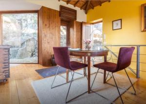 a dining room with a table and two purple chairs at Casa Do Fragao in Bouro