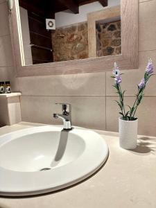 a bathroom sink with a vase with purple flowers at Lovinna Luxury Appartments in Kalymnos