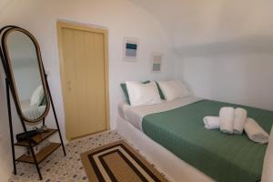 a small bedroom with a bed and a mirror at Villa Ariadni Cave Houses in Oia in Oia