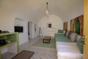 a living room with a green couch and a tv at Villa Ariadni Cave Houses in Oia in Oia