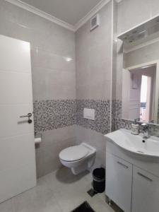 a white bathroom with a toilet and a sink at Apartment Allure in Čapljina +16 photos