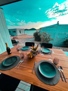 a wooden table with plates and wine glasses on it at MODERN BEACH VILLAS - Buqez Camp resort in Drage