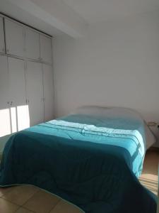 a bed with a blue comforter in a room at Las chismosas in Santiago del Estero