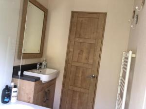 a bathroom with a wooden door and a sink at Large and comfortable, stylish caravan. in Bembridge