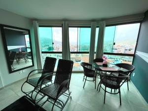 a dining room with a table and chairs and windows at Sophia I - Praia Grande in Arraial do Cabo