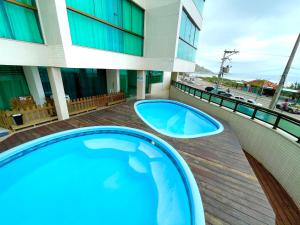 two hot tubs on a deck next to a building at Sophia I - Praia Grande in Arraial do Cabo