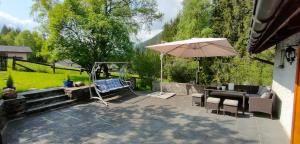 een patio met een tafel en een parasol bij [Chalet Villa Maria] con Vista Montagne - Netflix in Mesocco