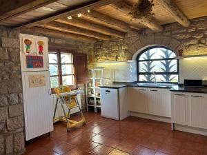 a kitchen with white appliances and a stone wall at Vila-seca, vine i desconnecta! in Aguilar de Segarra