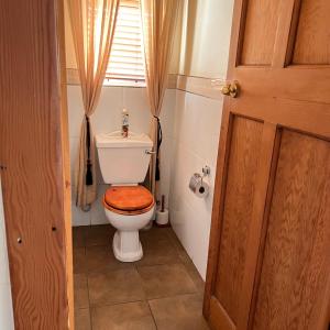 La salle de bains est pourvue de toilettes et d'un siège en bois. dans l'établissement Peaceful@Swansea In Rosebank-Parkwood, à Johannesbourg