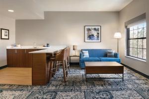 a living room with a blue couch and a table at Four Points by Sheraton Raleigh Arena in Raleigh