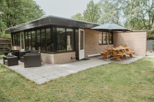 een klein huis met een picknicktafel en een paraplu bij Boshuisje Rekem - Rivus in Lanaken
