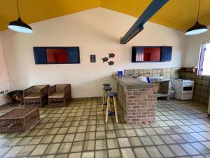 a kitchen with a counter and chairs in a room at Casa Saberé - 100m da Praia - 2 Suítes - 4 adultos in Porto De Galinhas
