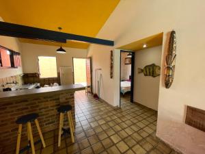 a kitchen with a counter and stools in a room at Casa Saberé - 100m da Praia - 2 Suítes - 4 adultos in Porto De Galinhas