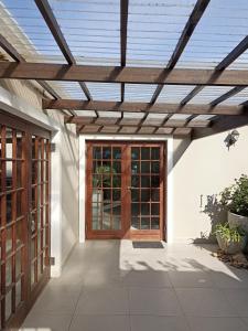 a wooden pergola over a front door of a house at Fijnbos Guesthouse in Knysna