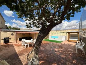 un patio con un árbol, una mesa y sillas en Casa rural cerca Tarancón-Cuenca, en Saelices