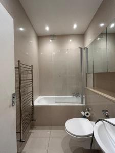 a bathroom with a tub and a toilet and a sink at Marble Arch Apartment, 2-Bedroom in London