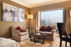 um quarto de hotel com duas cadeiras e uma cama e uma janela em Le Meridien Jeddah em Jeddah