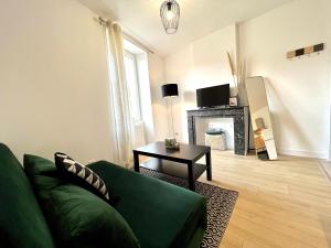 ein Wohnzimmer mit einem grünen Sofa und einem Tisch in der Unterkunft Suite ~ Romance Estivale ~ à 15 min de Lyon in Miribel