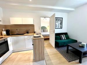 eine Küche und ein Wohnzimmer mit einem Sofa und einem Tisch in der Unterkunft Suite ~ Romance Estivale ~ à 15 min de Lyon in Miribel