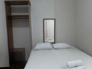1 cama con 2 almohadas blancas y espejo en APARTHOTEL CENTRAL MACAPÁ, en Macapá