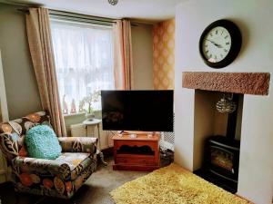 ein Wohnzimmer mit einem TV, einem Sofa und einer Uhr in der Unterkunft House - Alton Towers,Peak District,Wildlife Park in Leek