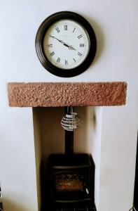 eine Uhr, die an einer Wand über einem Kamin hängt in der Unterkunft House - Alton Towers,Peak District,Wildlife Park in Leek
