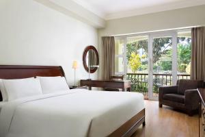 a bedroom with a bed and a chair and a window at Four Points by Sheraton Arusha, The Arusha Hotel in Arusha