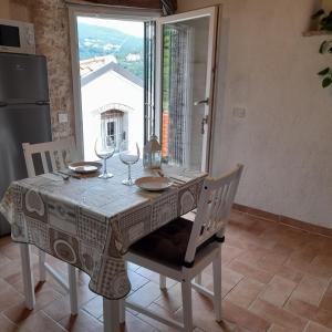 een eettafel met wijnglazen en een raam bij Cà di Pippo "Riccio" appartamento Loc Boragni Orco Feglino in Vezzi Portio
