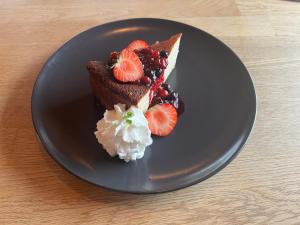a black plate with a piece of cake and fruit at Engimyri Lodge in Akureyri