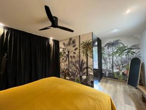 um quarto com uma cama amarela e uma ventoinha de tecto em La villa d'Eva em Léguillac-de-Lauche