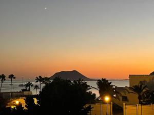 un coucher de soleil sur l'océan avec une montagne en arrière-plan dans l'établissement Alojamientos Playa Centro Corralejo 15, à Corralejo