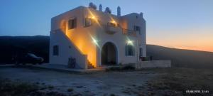 DendiánikaAposperitis Karavas的一座白色的大建筑,背面有日落