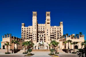 a large building with palm trees in front of it at Sheraton Sharjah Beach Resort and Spa in Sharjah