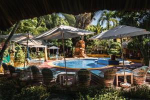 a swimming pool with chairs and umbrellas at Hotel Bungalows Acuario in Puerto Escondido