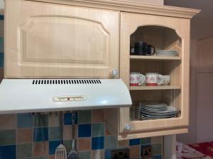a kitchen with a cabinet with a white hood and plates at Harman Suites Self-Catering Apartments Free WIFI & Parking in Leeds