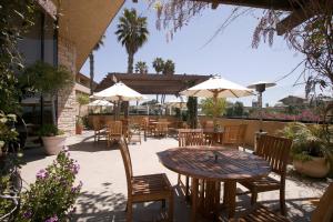 un patio con mesa, sillas y sombrillas en Four Points by Sheraton Ventura Harbor Resort, en Ventura